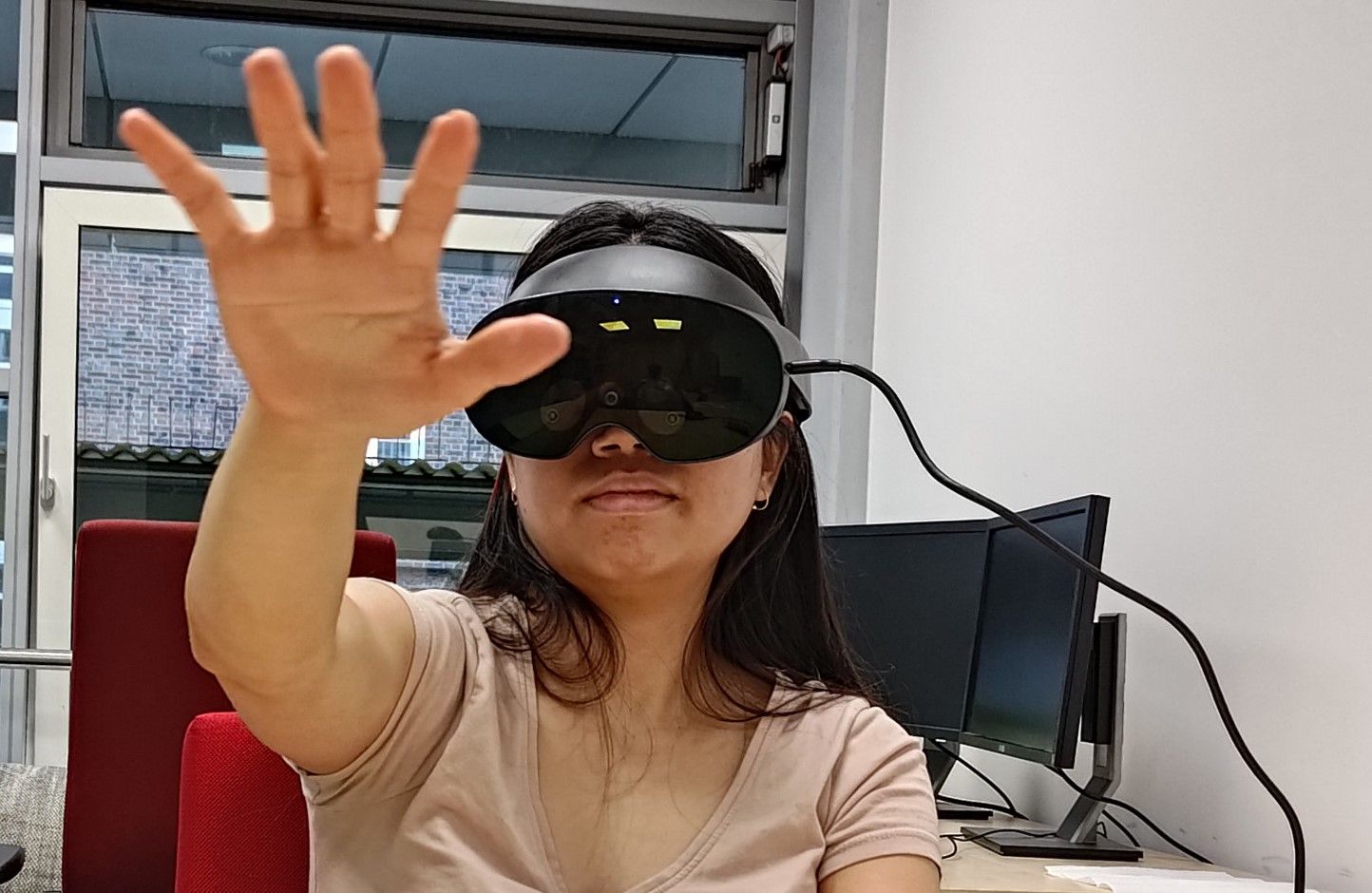 Person wearing a VR headset, reaching their hand out to touch a virtual object not visible  in the real world.